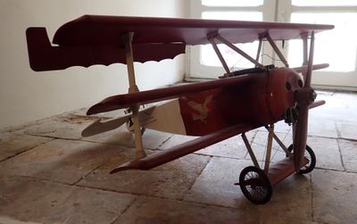 a small red airplane sitting on the floor in front of a door