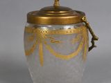 a glass jar with a gold decoration on the lid
