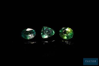 three green gems on a black background