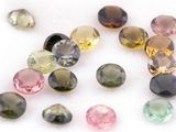 several different colored gems on a white surface with a white background