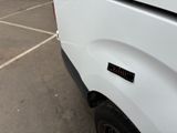 a white truck parked in a parking lot with other trucks in the background