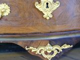 a brown dresser with gold handles on it in a room