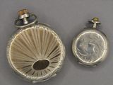 a silver pocket watch and a silver pocket watch on a table