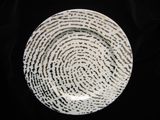 a white plate with black dots on it on a black background