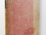 an old book sitting on top of a table next to a white wall