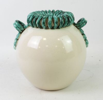 a white vase with a green decoration on top of it