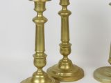 three gold candlesticks sitting on a white surface