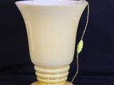 a yellow glass vase with a chain around it on a black background