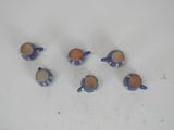 five small blue and orange teapots on a white surface