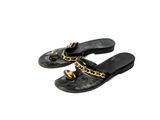 une paire de pantoufles noires ornées de chaînes dorées, posées sur un fond blanc