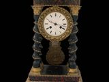une horloge posée sur un socle, sur fond noir
