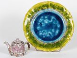 une assiette bleue et verte avec une théière à côté