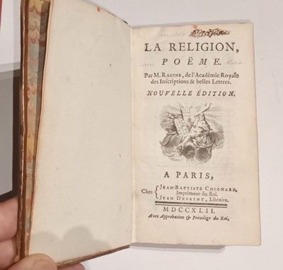 une main tenant un livre ouvert sur lequel figure l'image d'un oiseau