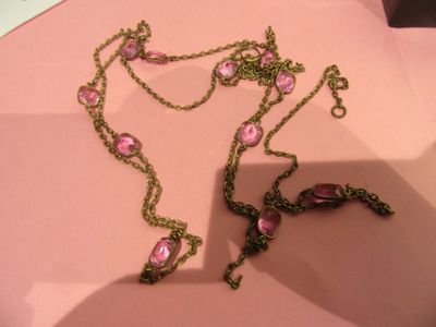 un collier rose orné de fleurs roses, posé sur un fond rose