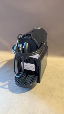 une petite cafetière noire posée sur une table blanche