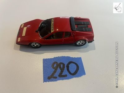 une petite voiture rouge posée sur une table, à côté d'une feuille de papier bleue