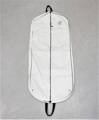 un sac à vêtements blanc posé par terre, muni d'une poignée noire