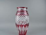 un vase en verre avec un socle rouge posé sur une surface blanche