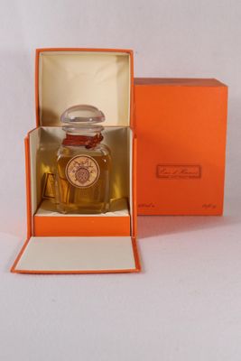 an orange box with a perfume bottle inside of it on a white surface