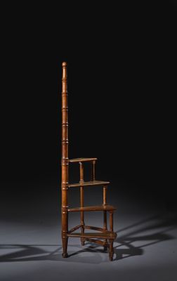 a wooden chair sitting on top of a gray floor next to a tall wooden pole