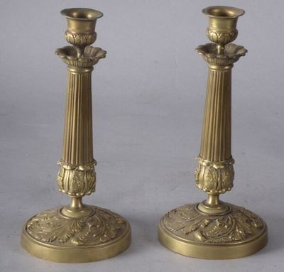 une paire de bougeoirs anciens en laiton sur socles, sur fond gris