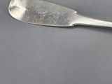 a silver spoon with a long handle on a gray surface