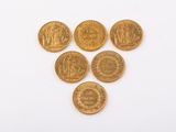 six gold coins are arranged in a triangle on a white surface