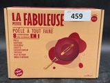 the box of a red pan with a wooden spatula on it