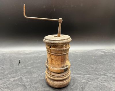 un vieux moulin à poivre en bois posé sur une table