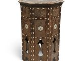 an old wooden side table with a carved top and a circular design