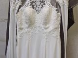 wedding dress hanging on a hanger in front of a stone wall