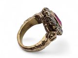 a close up of a gold ring with a pink stone