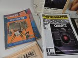 newspapers and magazines on a table with a camera on top of them