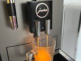 a cup of orange juice being poured into a coffee machine