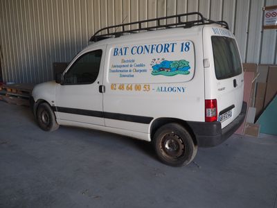 une camionnette blanche garée dans un garage, avec une pancarte à l'arrière