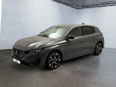 La voiture grise est garée dans une grande pièce aux murs blancs.
