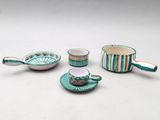 four pieces of tea set on a table with a cup and saucer