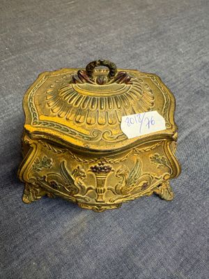 gold plated box with a price tag on it sitting on a blue cloth