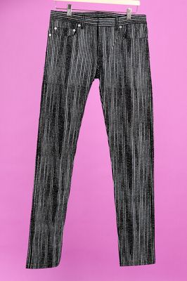 un pantalon rayé noir et blanc suspendu à un cintre sur fond rose