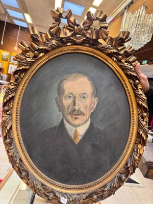 un homme tenant un tableau représentant un homme en costume