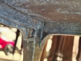 a close up of a metal table with a red car in the background