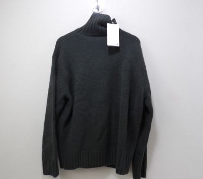 un pull noir suspendu à un cintre accroché au mur