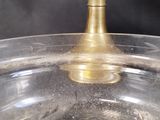 a glass bowl with a gold candle holder on top of it