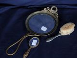 une photo représentant un miroir et une brosse posés sur un lit