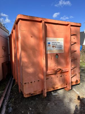 an orange dumpster sitting in the middle of a yard