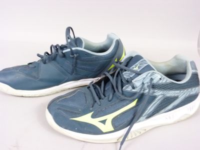une paire de chaussures de tennis bleues avec des touches de jaune sur un fond blanc