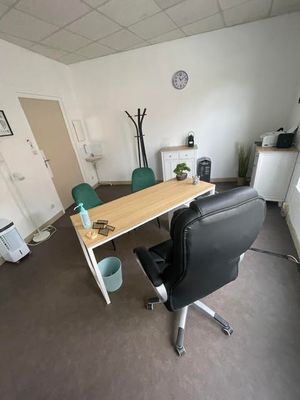 un bureau et une chaise dans une pièce où est accrochée une horloge au mur