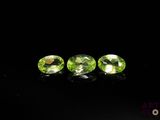 three green peridotites on a black surface
