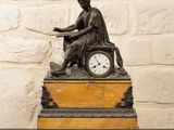 une statue représentant une femme assise sur une horloge posée sur une table