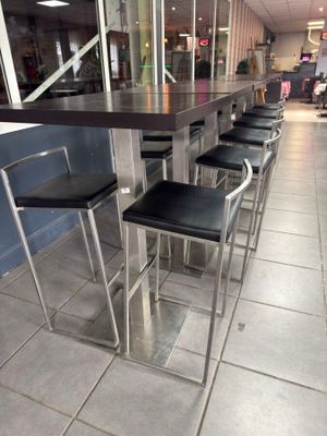 une rangée de tabourets de bar en cuir noir alignés devant le comptoir d'un restaurant